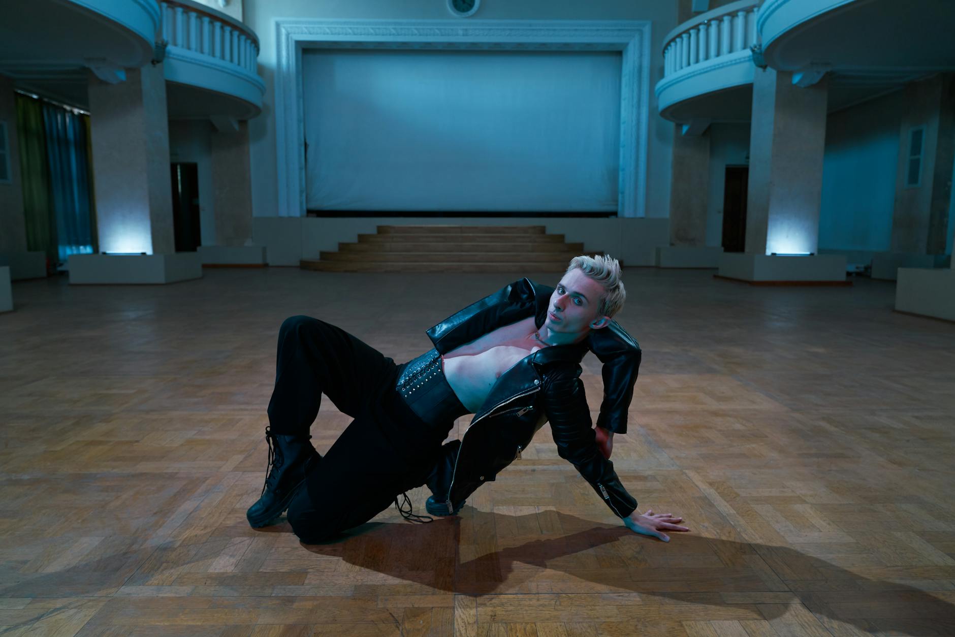 A dynamic dance performance with a performer posing on the stage of a modern indoor hall.