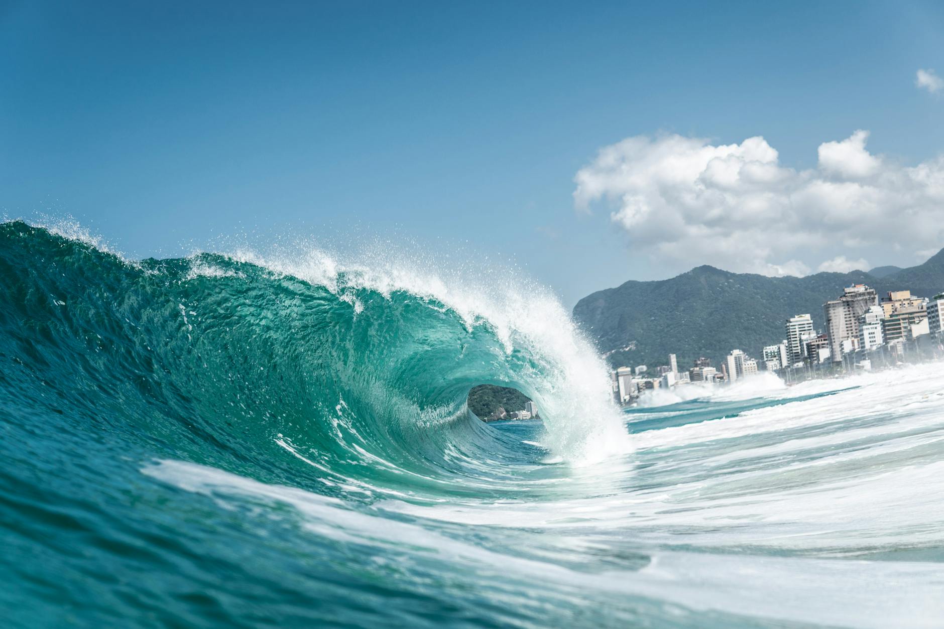 Dynamic ocean wave crashing near Ipanema Beach, Rio de Janeiro under a clear sky.
