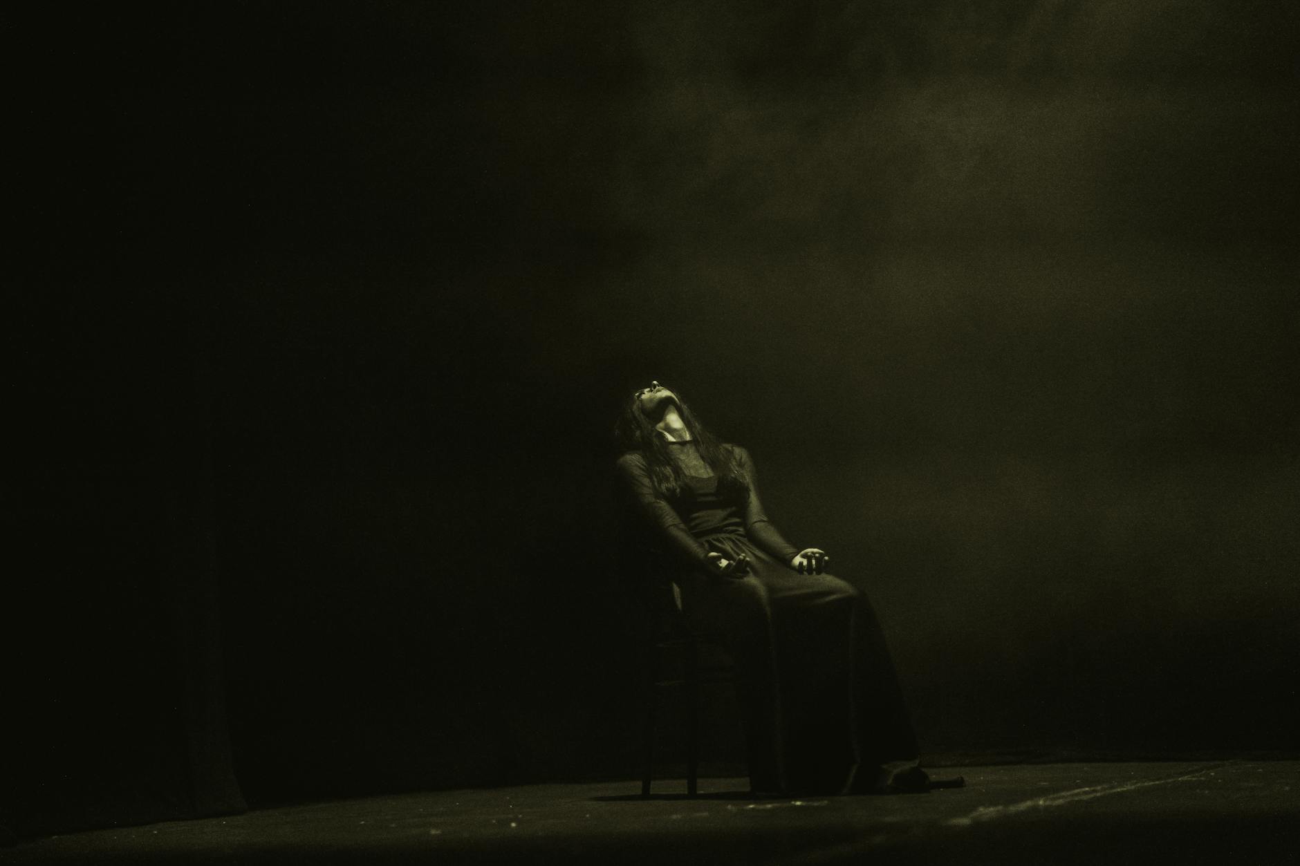 Moody stage performance with dramatic lighting and shadows, capturing a solo female artist in contemporary dance.