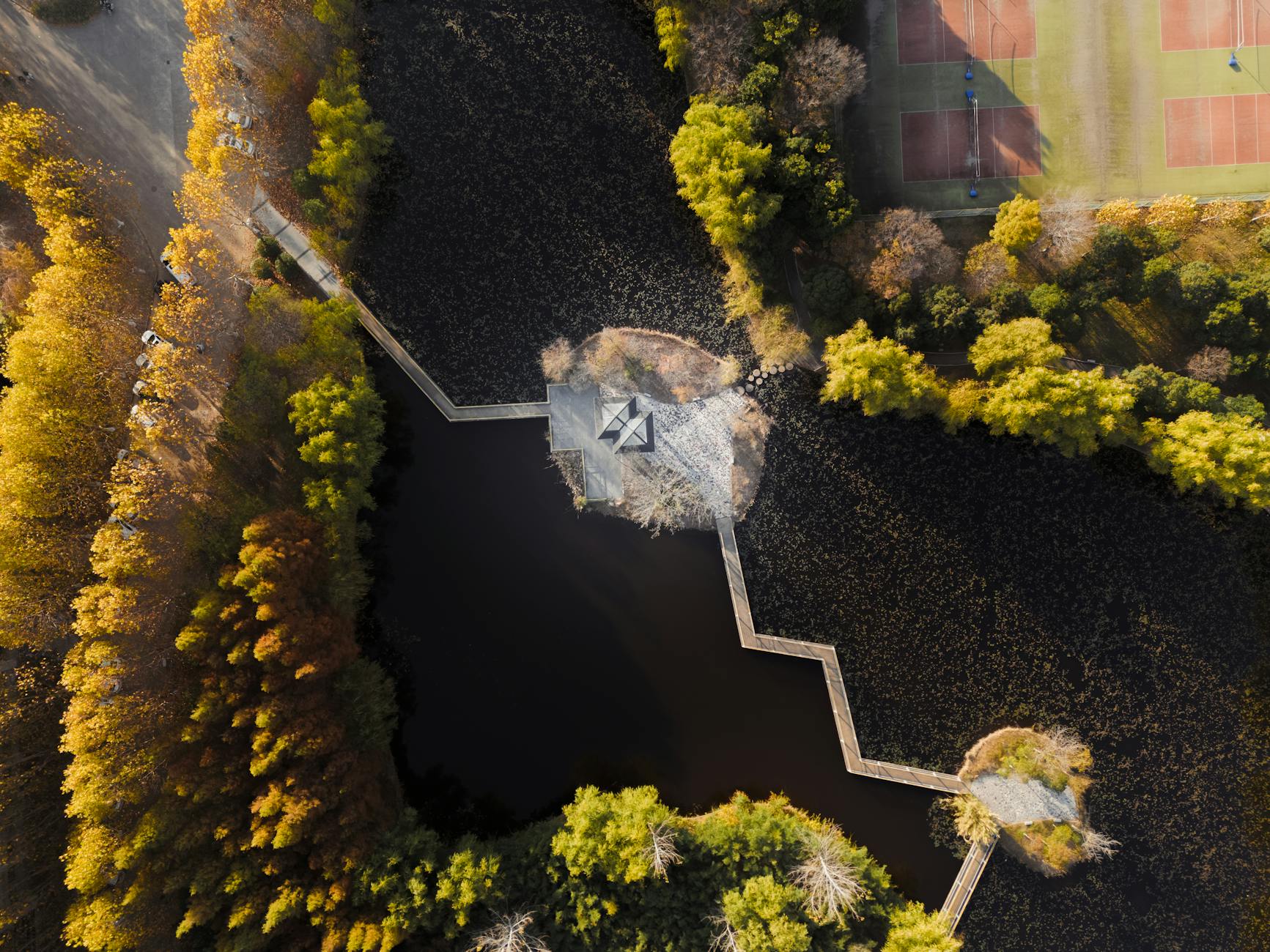 Stunning aerial shot of a park in Nanjing, Jiangsu, China, showcasing a water feature and tennis courts.