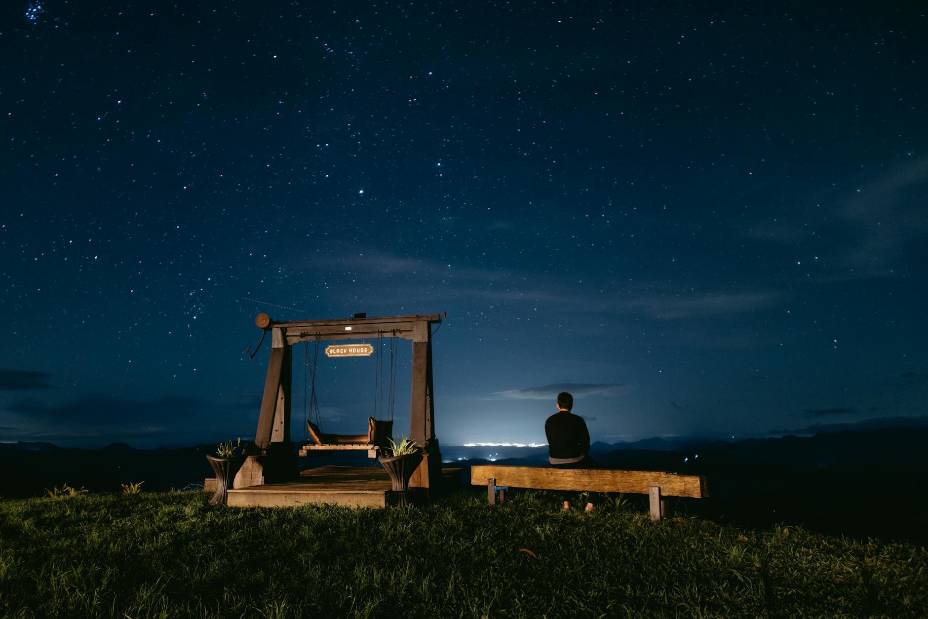 A serene night view of a person stargazing in Santa Teresa, Brazil, under a vast starry sky.