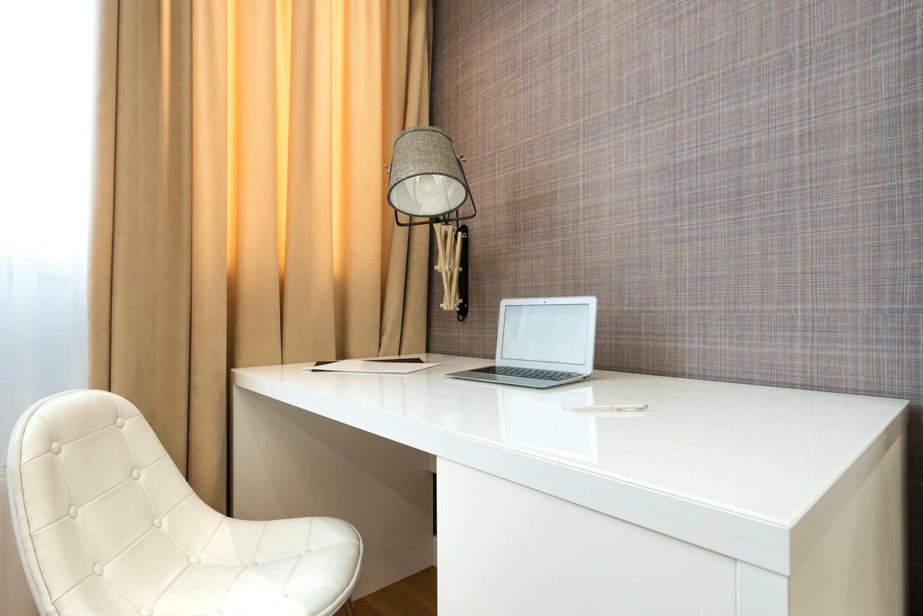 Stylish modern workspace featuring a laptop on a sleek desk with an elegant white chair and ambient lighting.