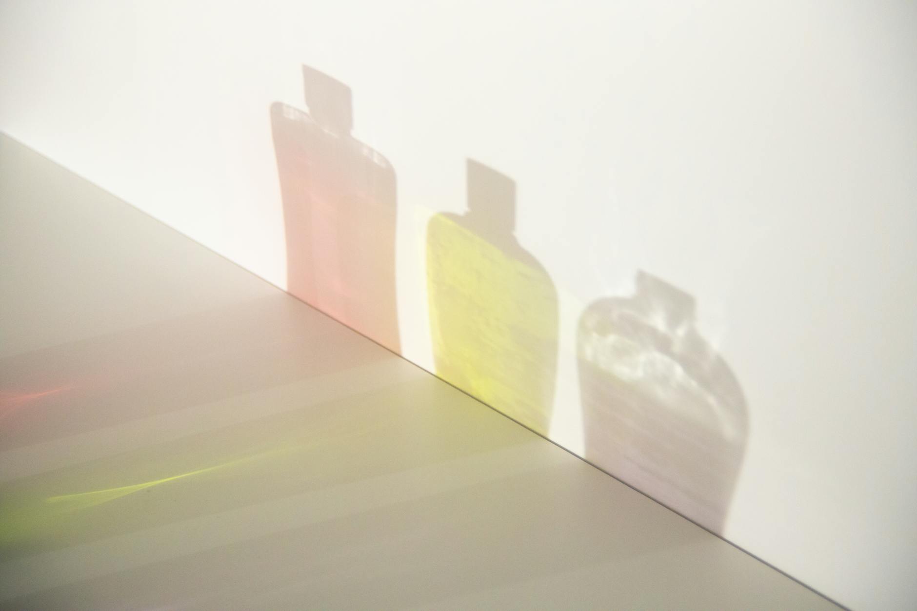 From above of different bottle shadows with bright liquids and caps in row on smooth surface