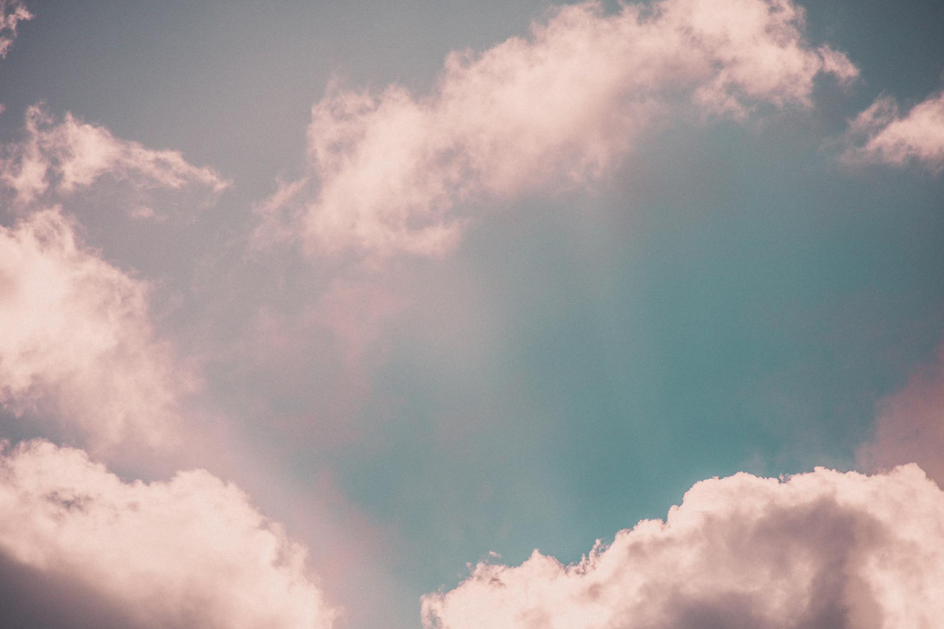 A serene and ethereal cloudscape with soft pink clouds against a pastel sky, evoking calmness.