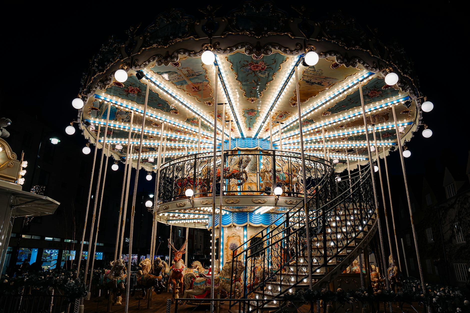 A beautifully lit carousel glows against the night sky in Oxford, England, capturing a magical fairground scene.