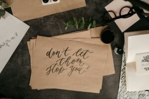 Flat lay of motivational calligraphy with eucalyptus and ink on rustic background.