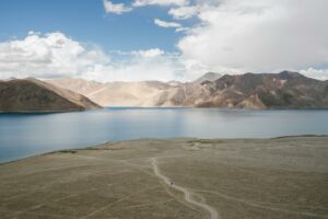 Aerial view of a tranquil lake surrounded by rocky mountains under a clear sky, showcasing vast natural serenity.