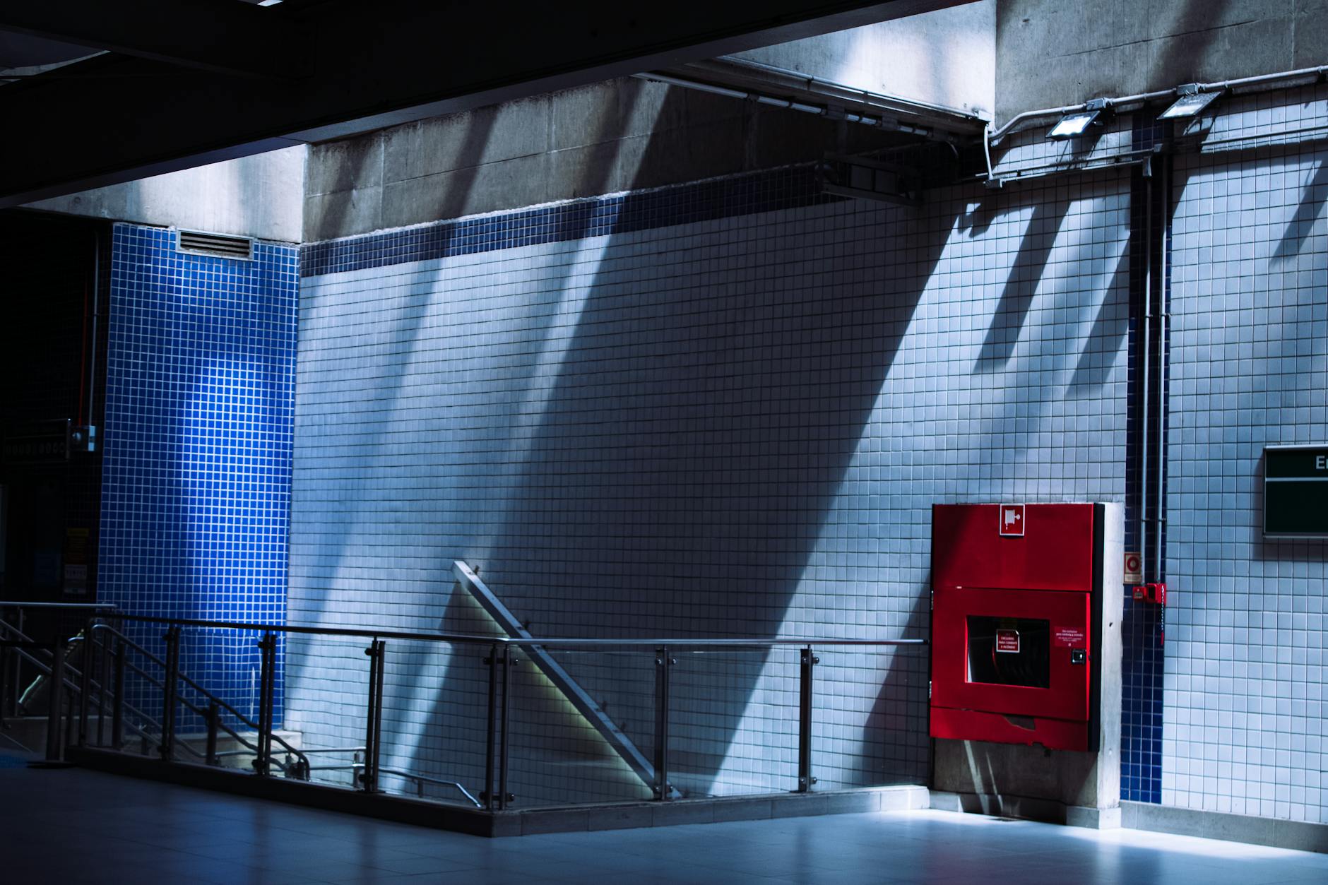 Sunlit tiled subway station interior in São Paulo with a red fire cabinet.